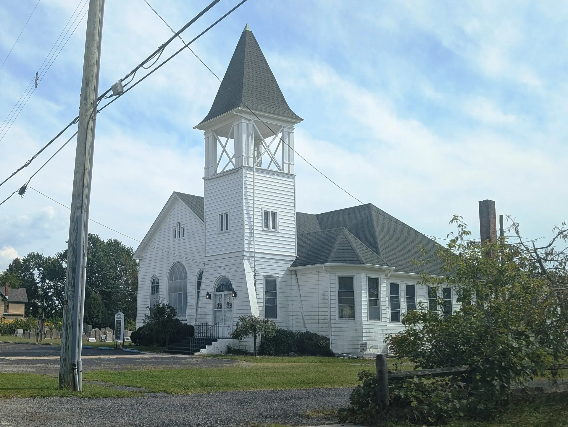 Newport United Methodist Church is a white church with a clock in its tall belfry and a side annex.