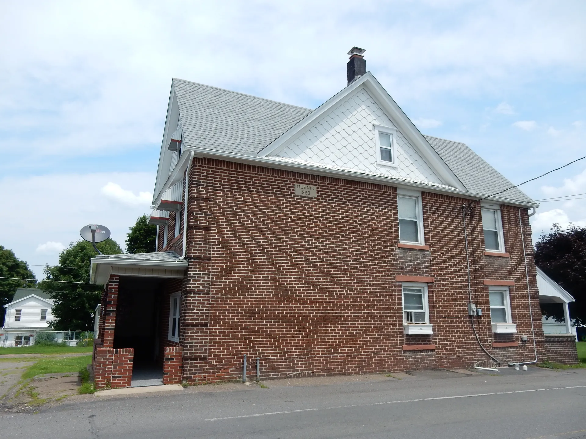 A two-and-a-half-story brick home with a white gabled roof and side entry sits on Market Street in Kelayres.