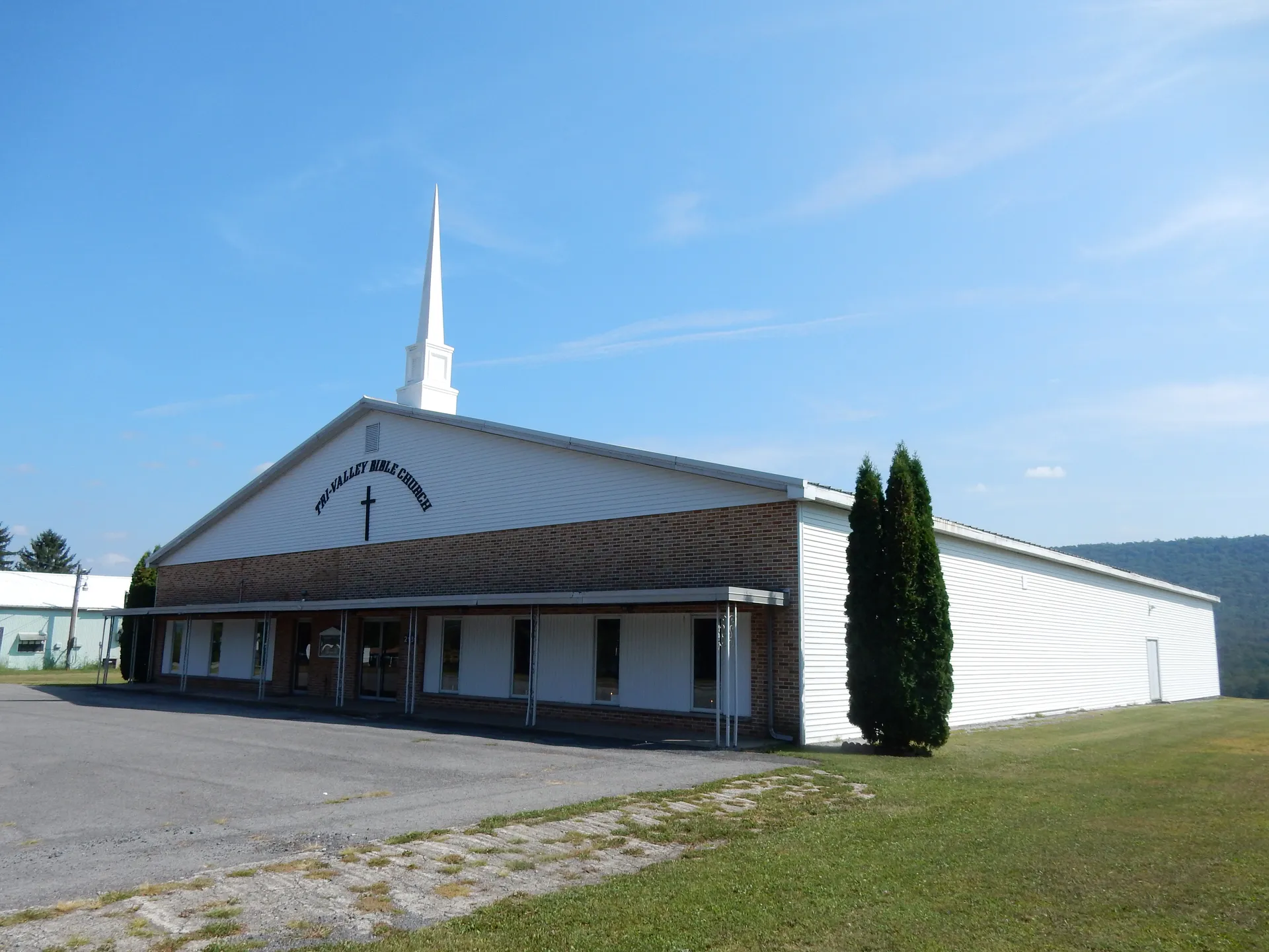 Tri-Valley Bible Church in Hubley Township is a long gray building with a slender white steeple on East Main Street.
