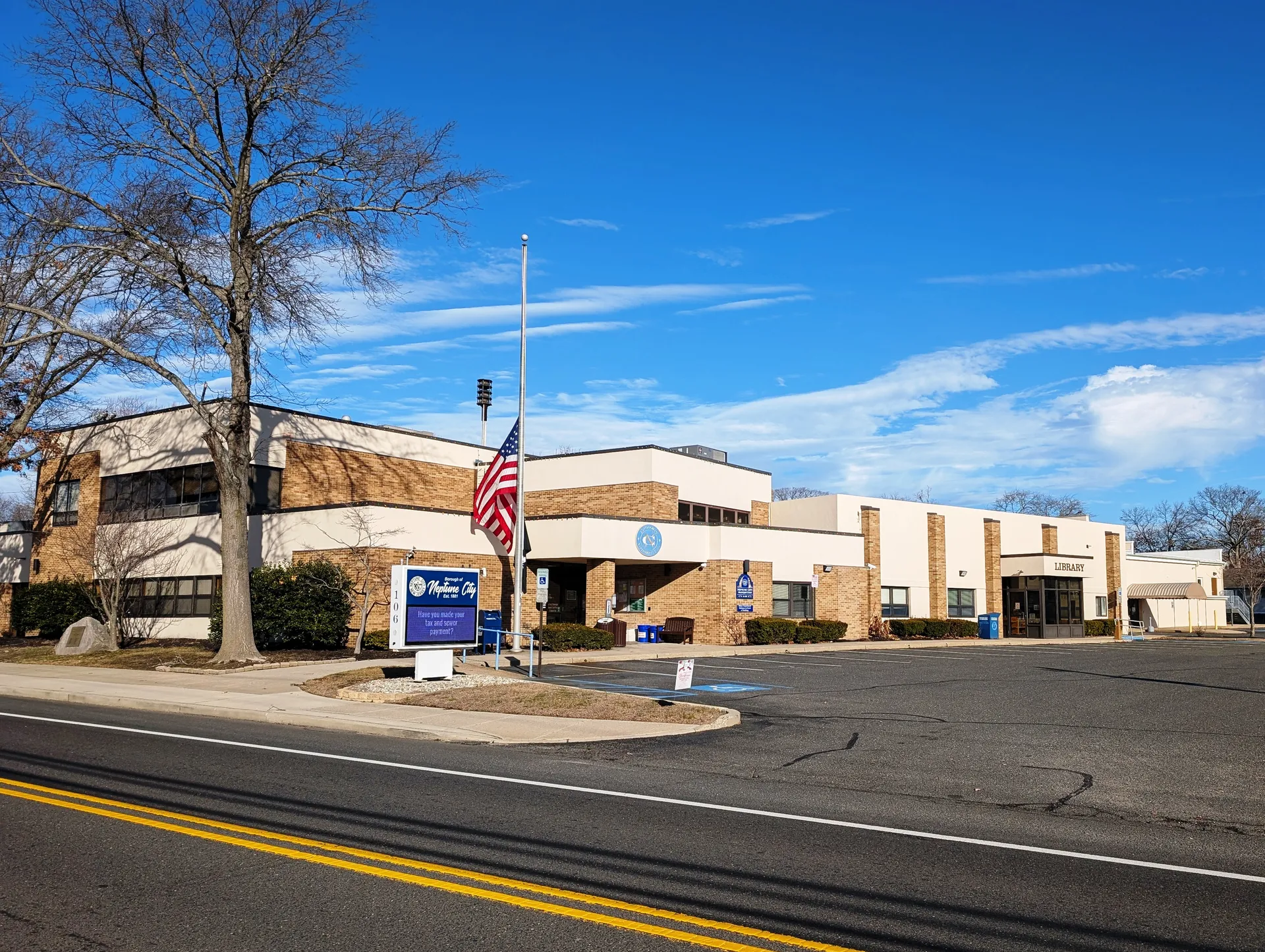 The Neptune City municipal building is a long tan building with a flagpole at the end of a curving drive.