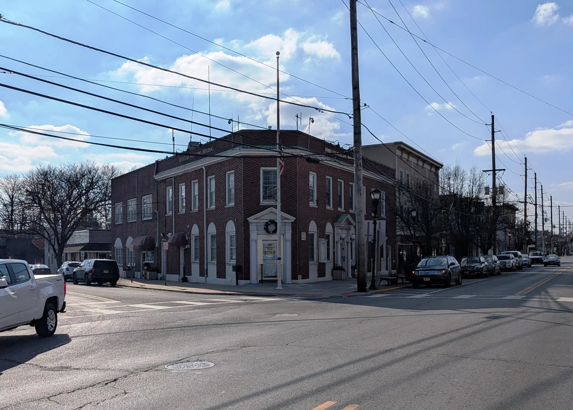 Dunellen's municipal building is a red brick structure with white-trimmed arched windows and a wreath above the door on a street corner.