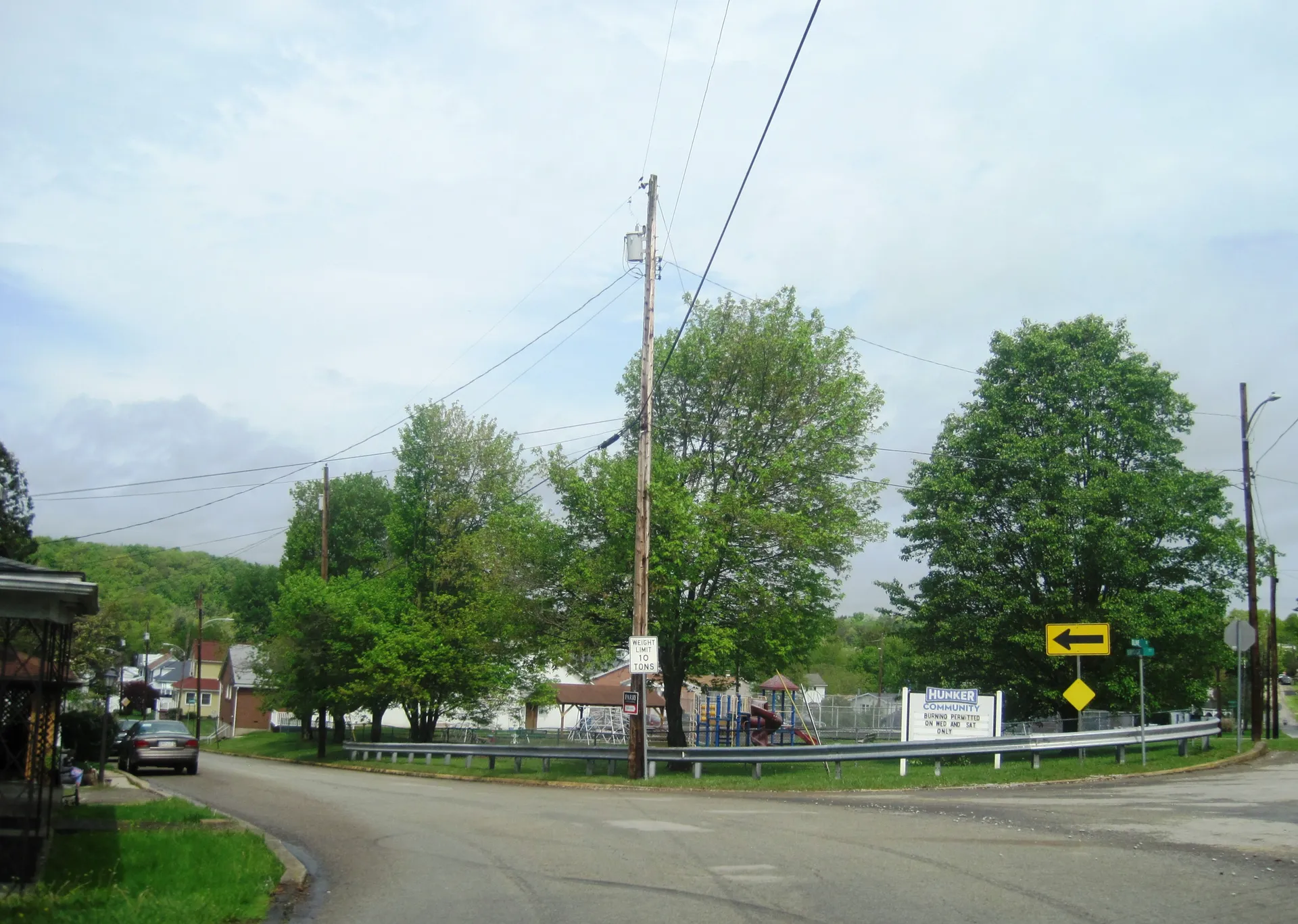 Bridge Street in Hunker meets Weltz Avenue and Olive Street, with a borough park and trees beside the road.