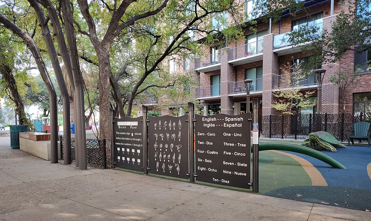 Play equipment and shaded paths at Yanaguana Garden in Hemisfair, north of Lavaca, photographed in December 2025.