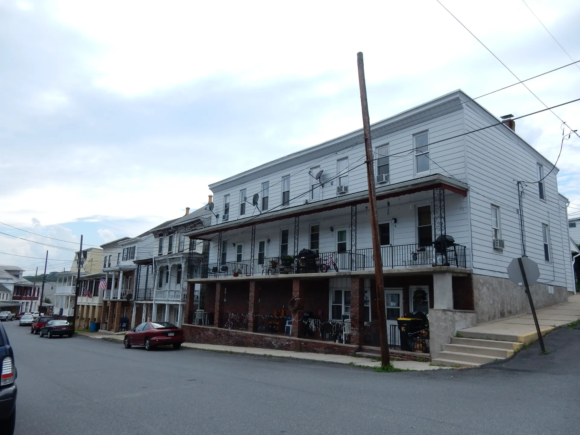 A long multi-story porch building lines Coal Street at Wood Street in Cumbola, where the village post office occupies one of the houses.