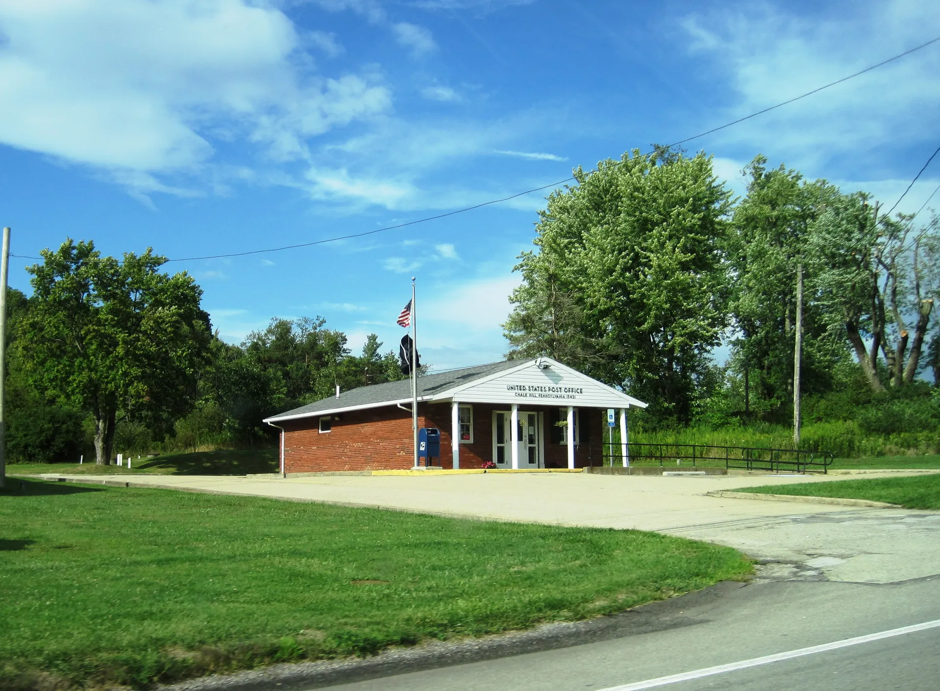The Chalk Hill post office is a small brick building with a white-columned portico and a flag, set on a broad lawn.