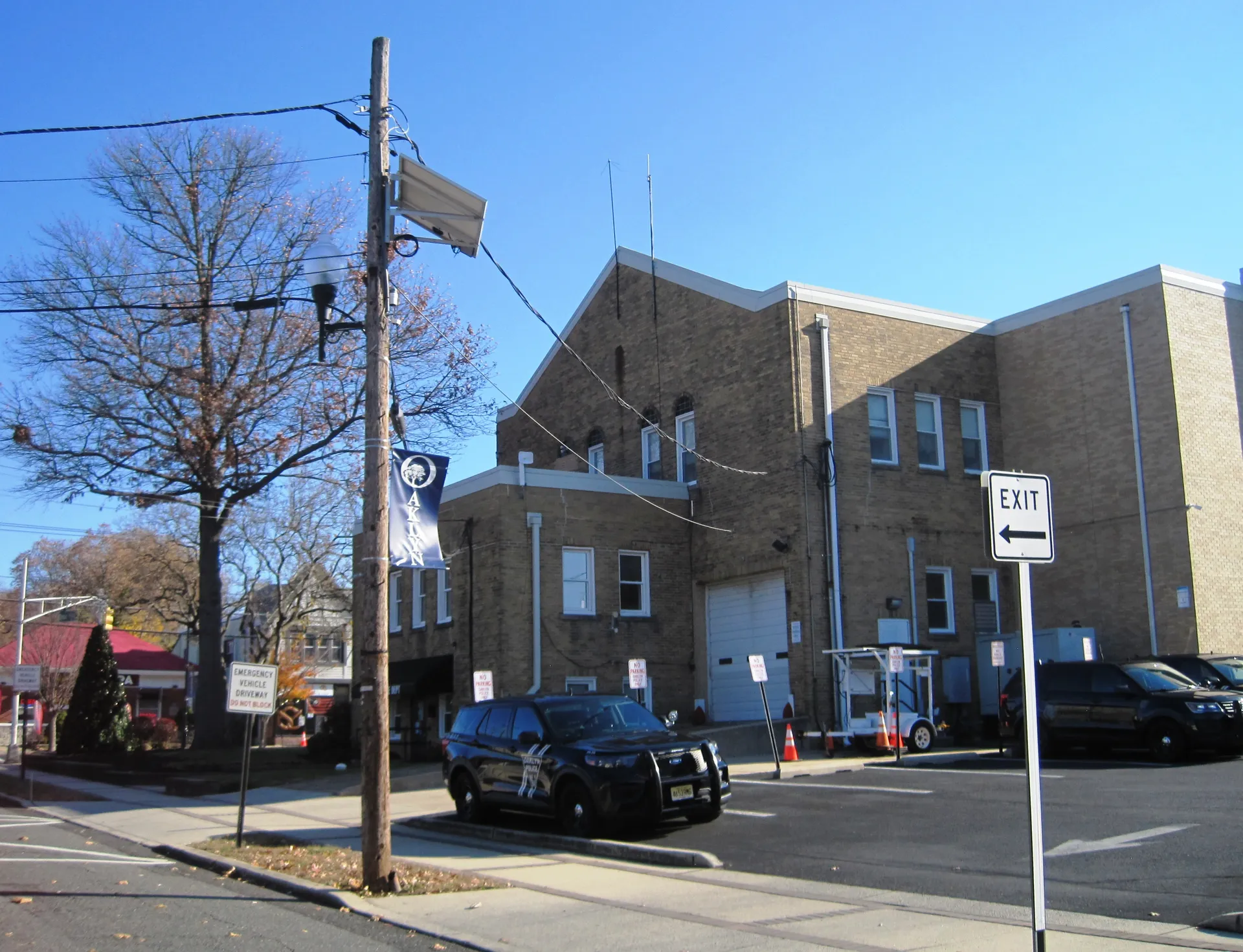 Oaklyn's borough hall and police station share a tan brick building with a squad car parked out front.