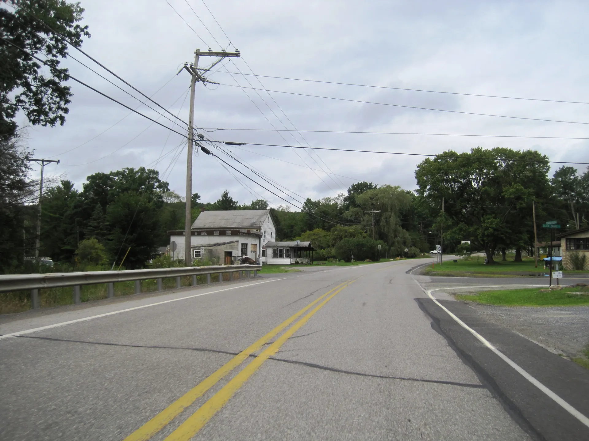 Route 53 approaches Black Snake Road in Dysart, a village in Dean Township, passing a white house and utility lines.