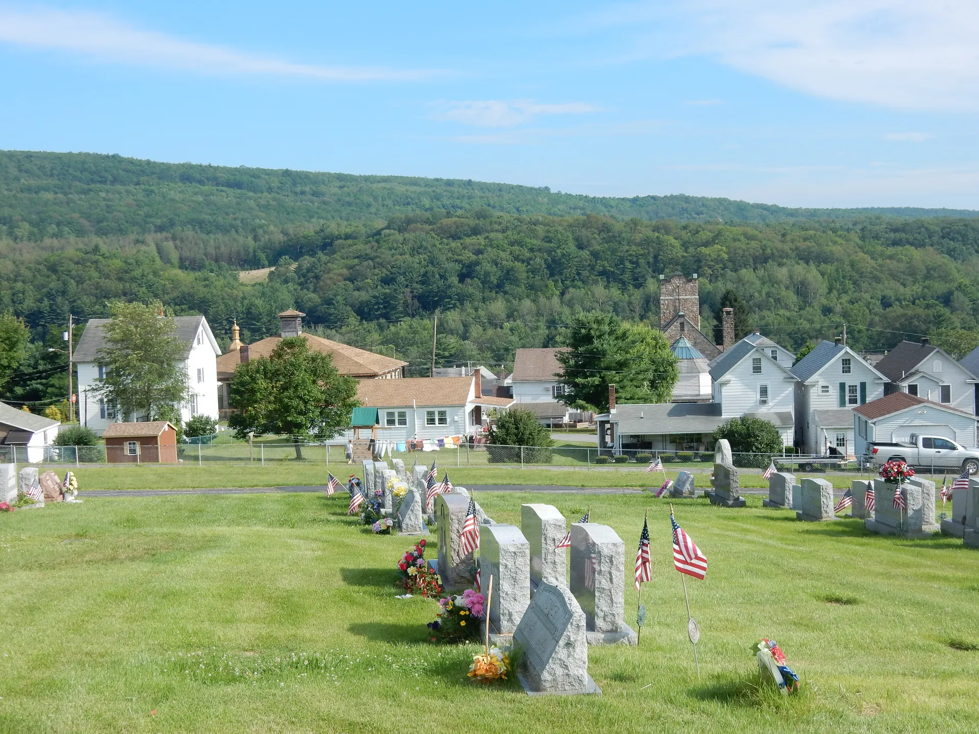 Flag-decorated headstones in St. Bartholomew's Cemetery look out over the rooftops of Brockton and the wooded hills of Schuylkill Township.