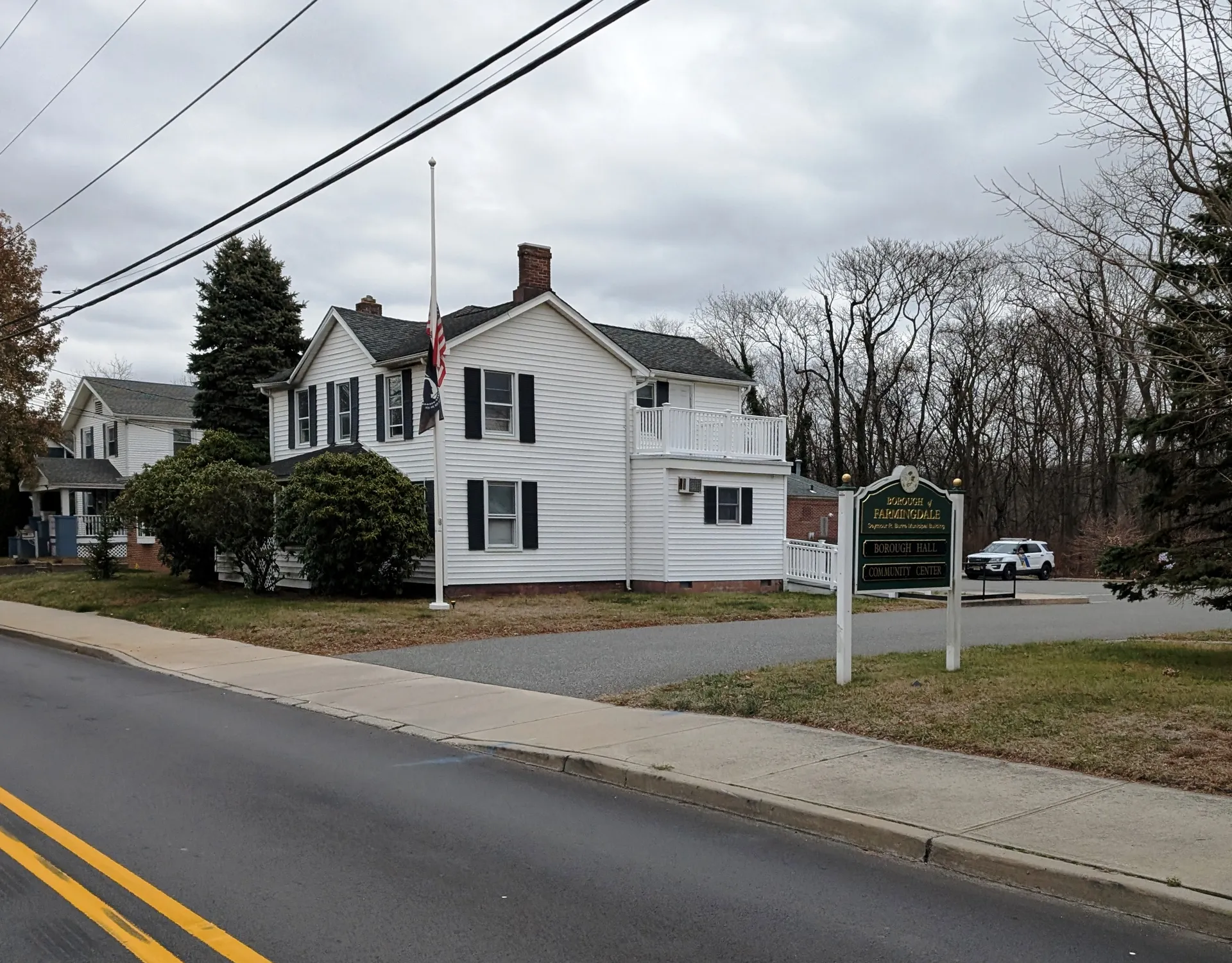 Farmingdale's municipal building is a white two-story frame house with black shutters and a front porch on a corner lot.