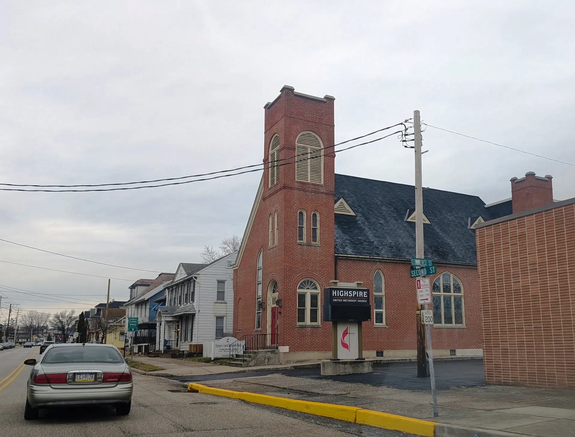 Highspire United Methodist Church features a tall red-brick bell tower and dark roof facing the main road through town.
