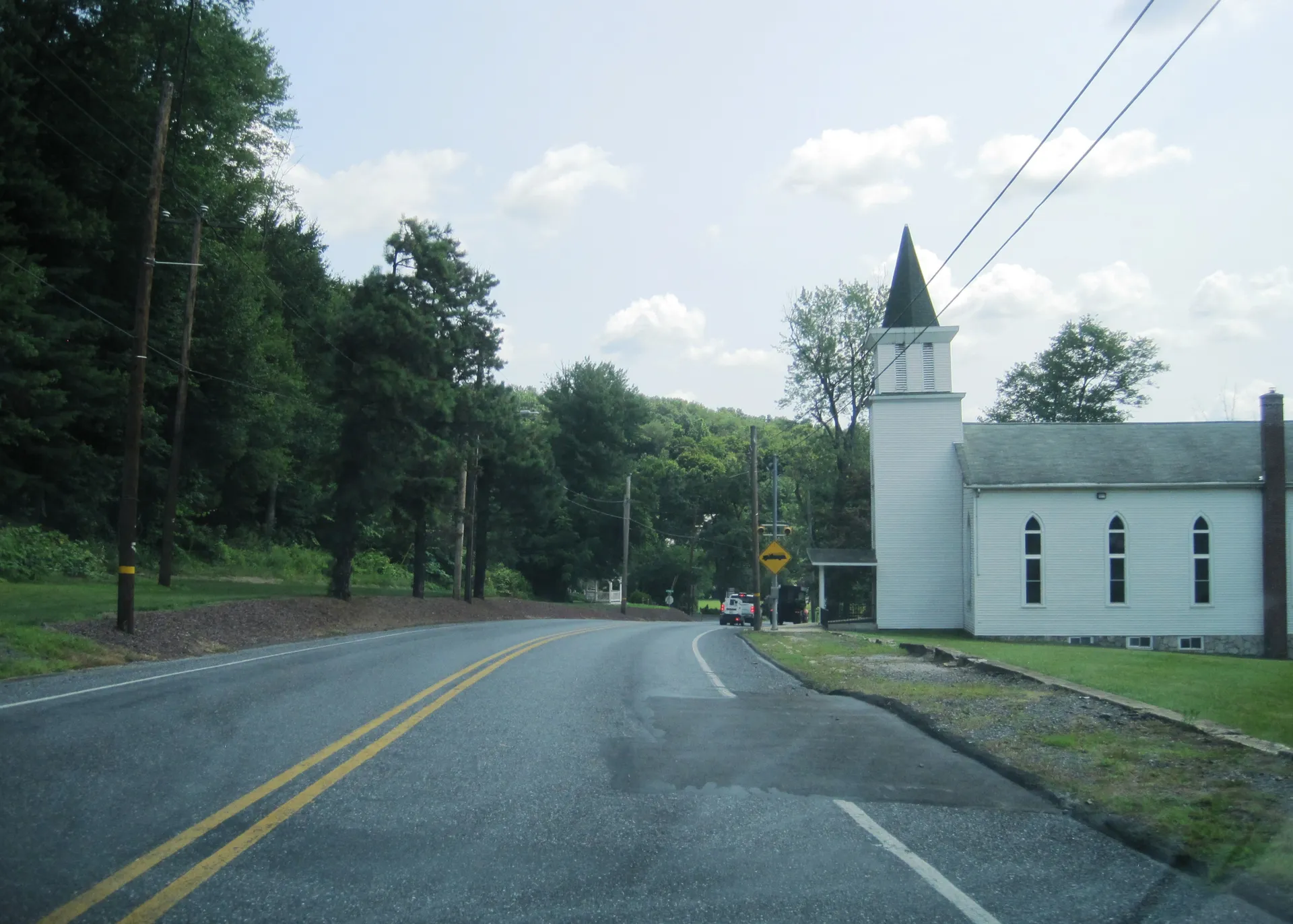U.S. Route 209 curves past a white church with a tall steeple in Branchdale, a village in Reilly Township, Schuylkill County.