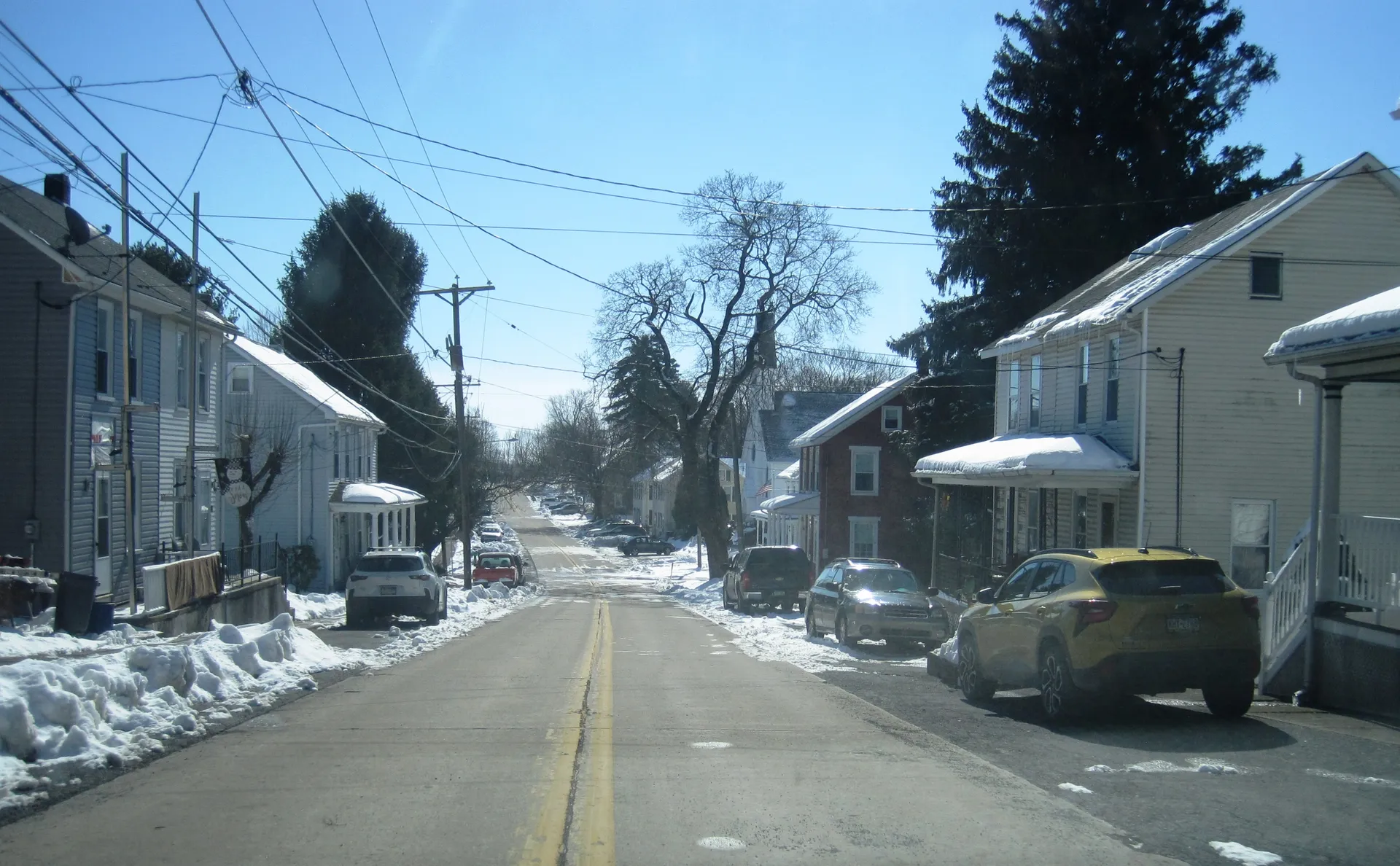 Main Street in Chapman runs south between 6th and 7th streets past houses and parked cars, with snow along the curbs.