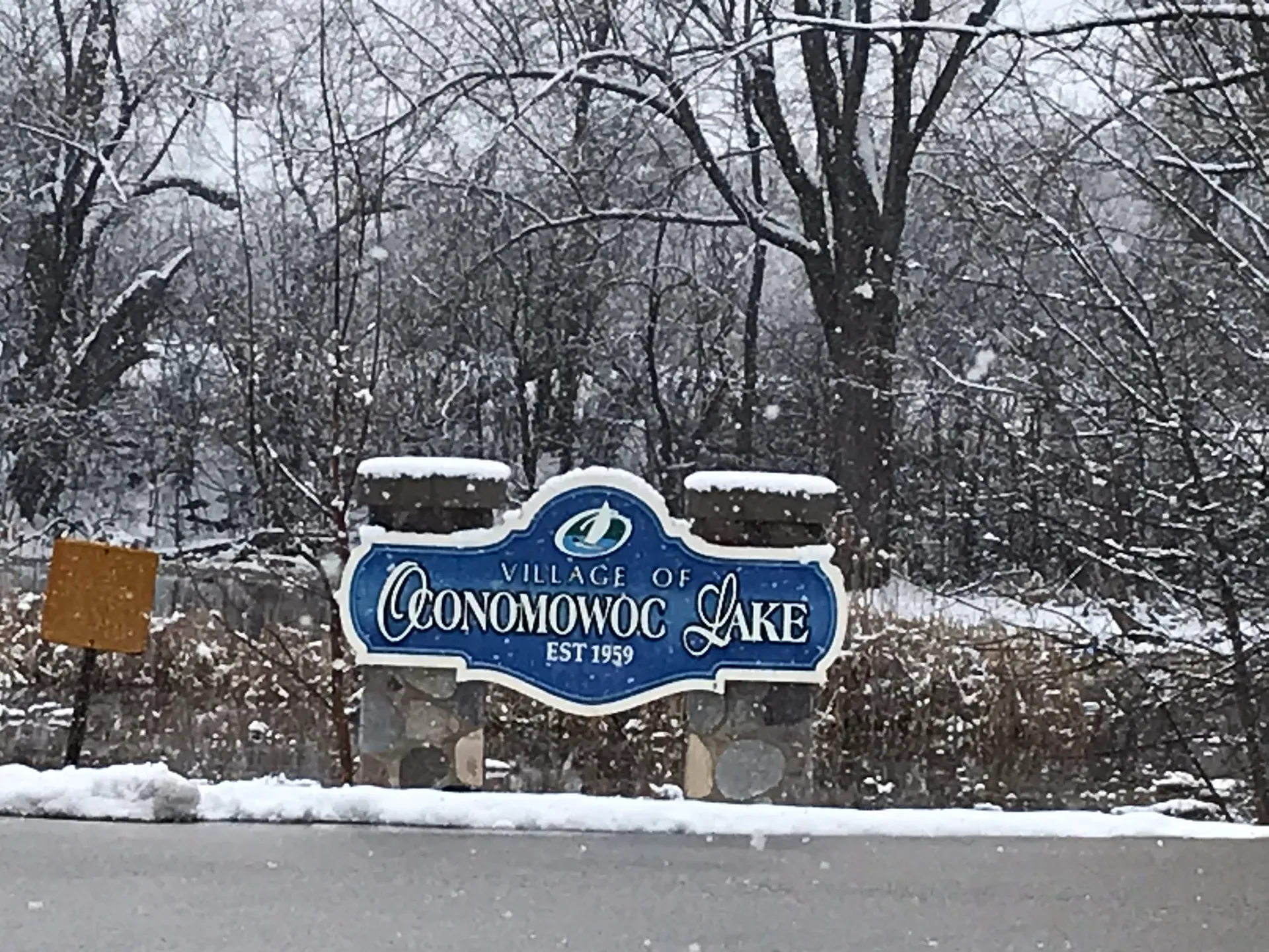 Oconomowoc Lake welcome sign in a snowy setting in Oconomowoc Lake, Wisconsin.