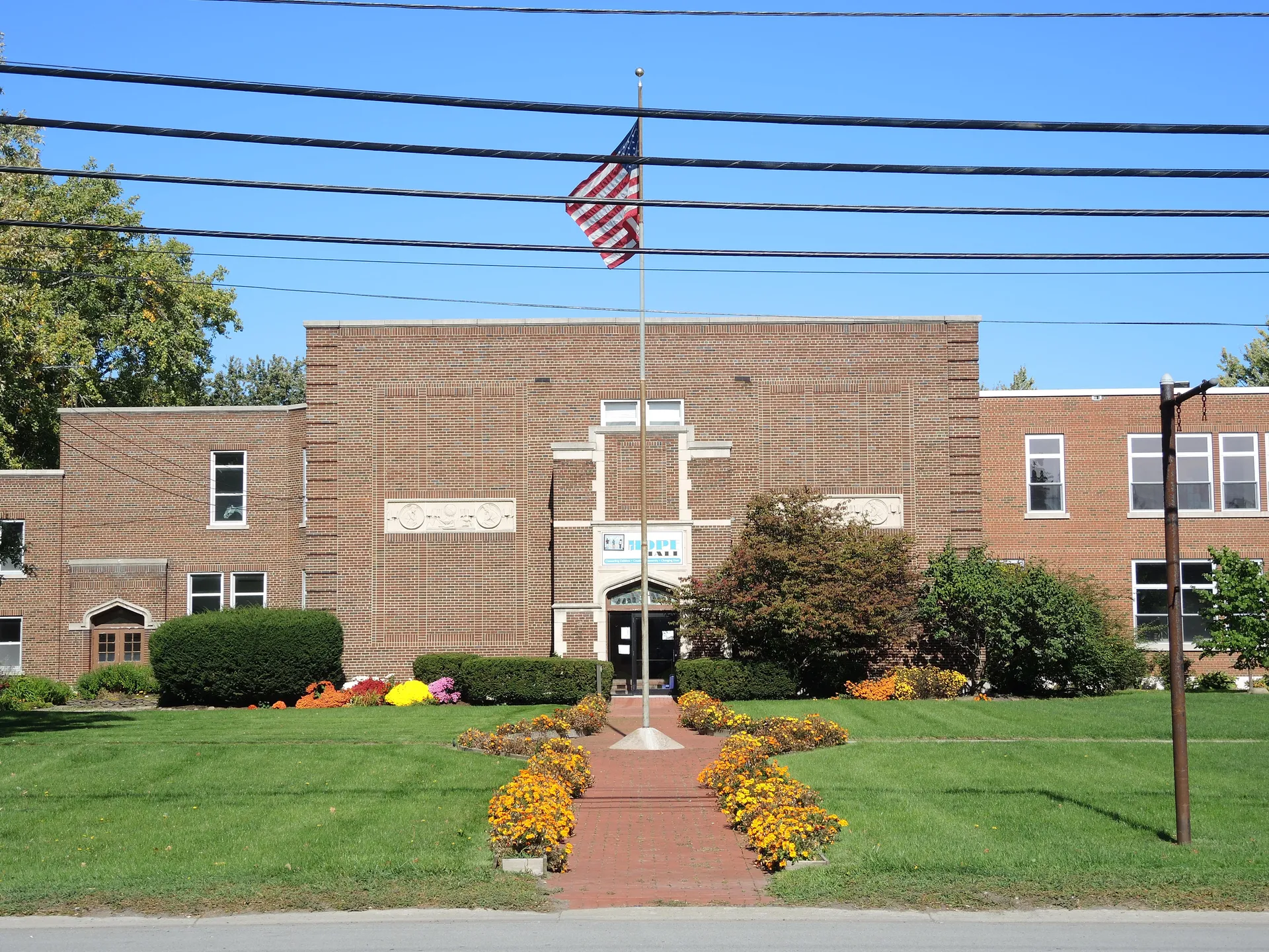 Brick Thomas Edison School entrance with flower beds in Gates, New York.