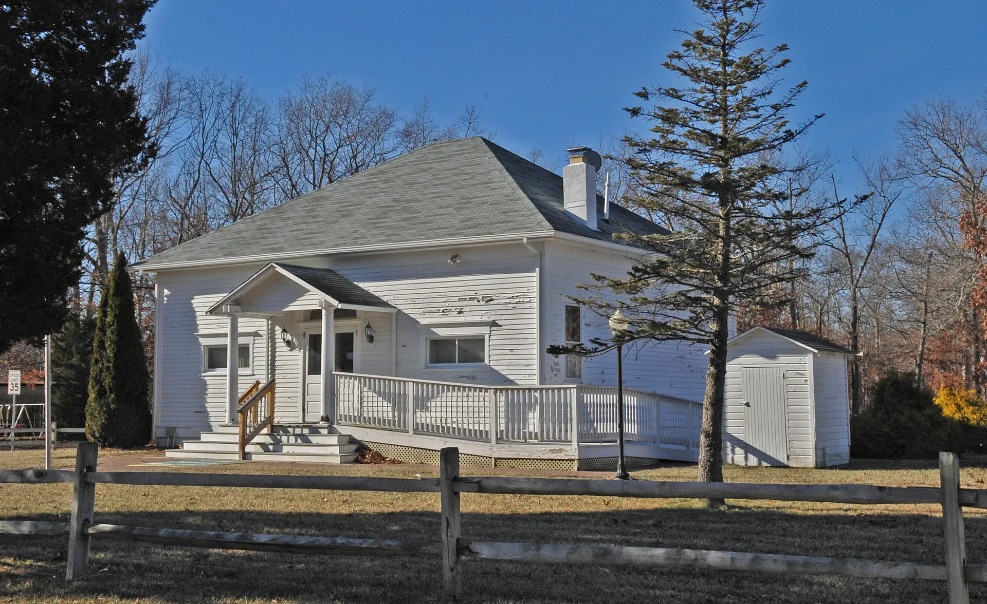 The Risley School in Estell Manor is a white clapboard schoolhouse with a hipped roof, a railed porch and a chimney.
