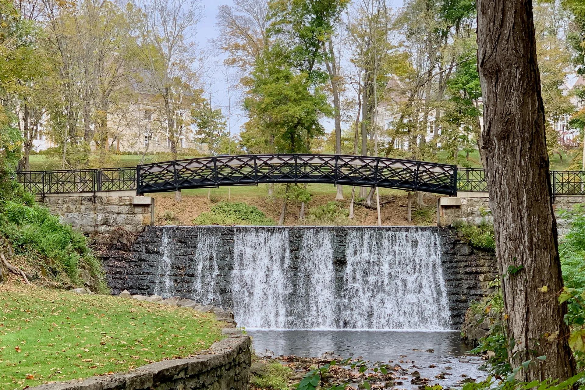 A decorative black iron footbridge spans the waterfall of a stone dam on the Blair Academy campus in Blairstown.