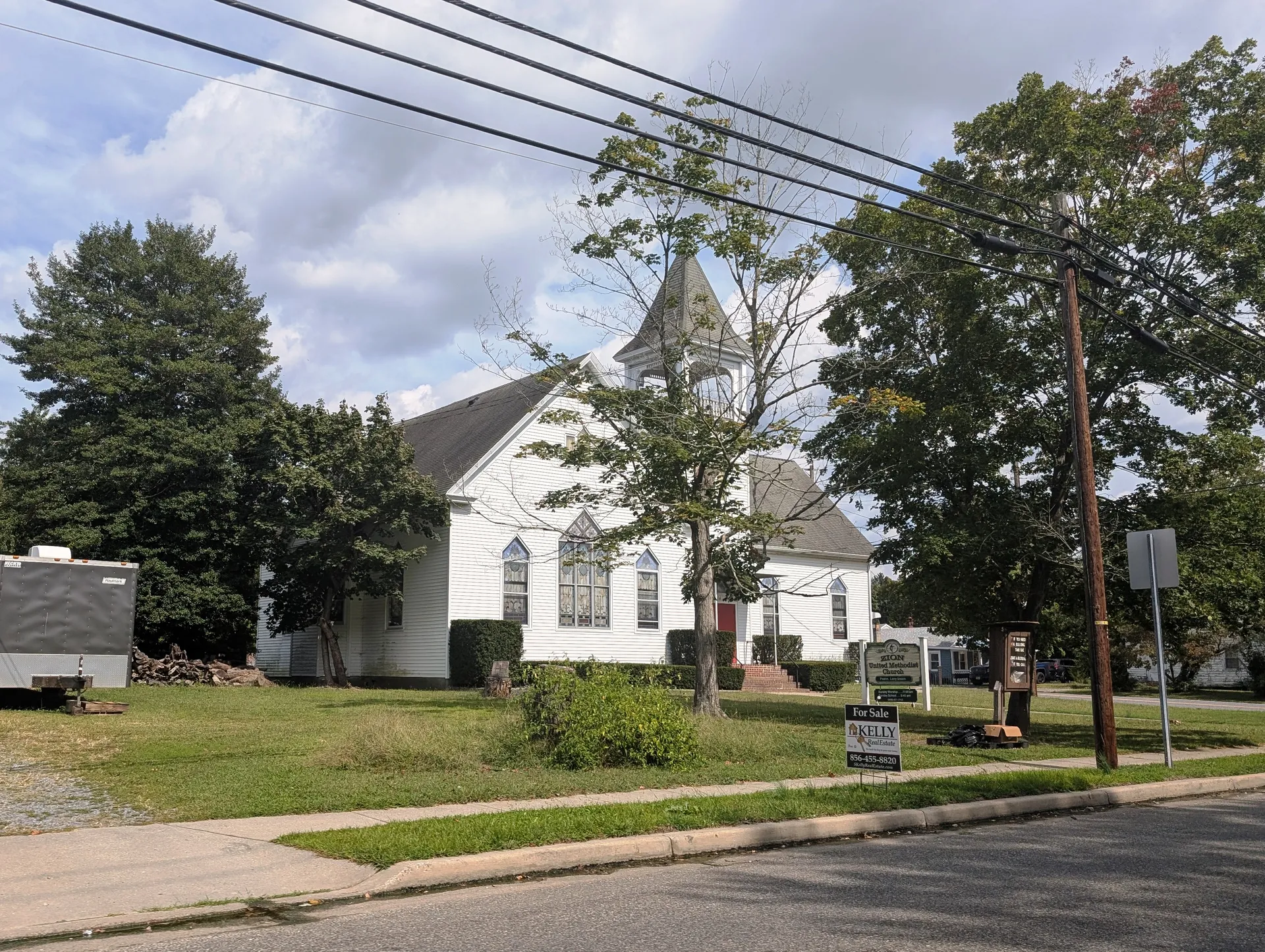 Zion United Methodist Church in Dividing Creek is a white Gothic-style church with a pointed steeple, set behind a sign and green lawn.