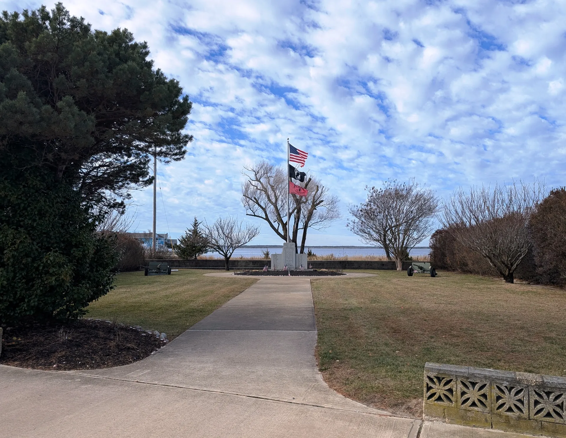 Lavallette's veterans memorial sits at the end of a curving walk with flags and the bay beyond.