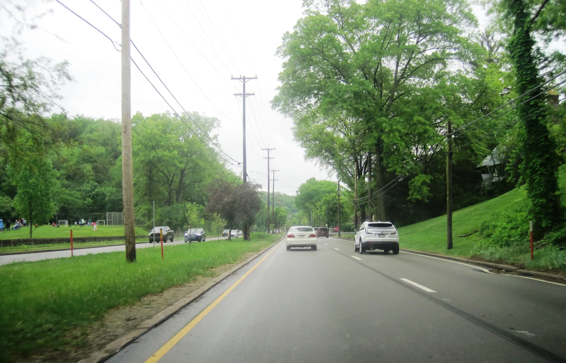 Ardmore Boulevard (U.S. Route 30) curves east through Forest Hills between Braddock Road and Leola Way past grassy slopes.