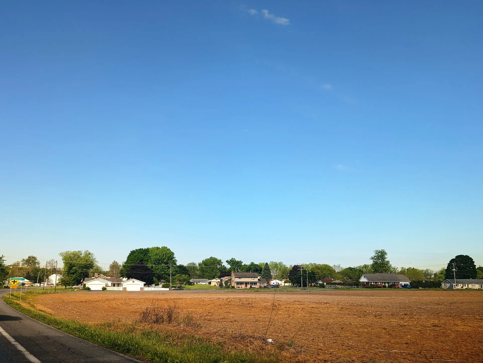 A row of houses lines Kohler Road in the village of Bowers in Maxatawny Township, seen across an open field.