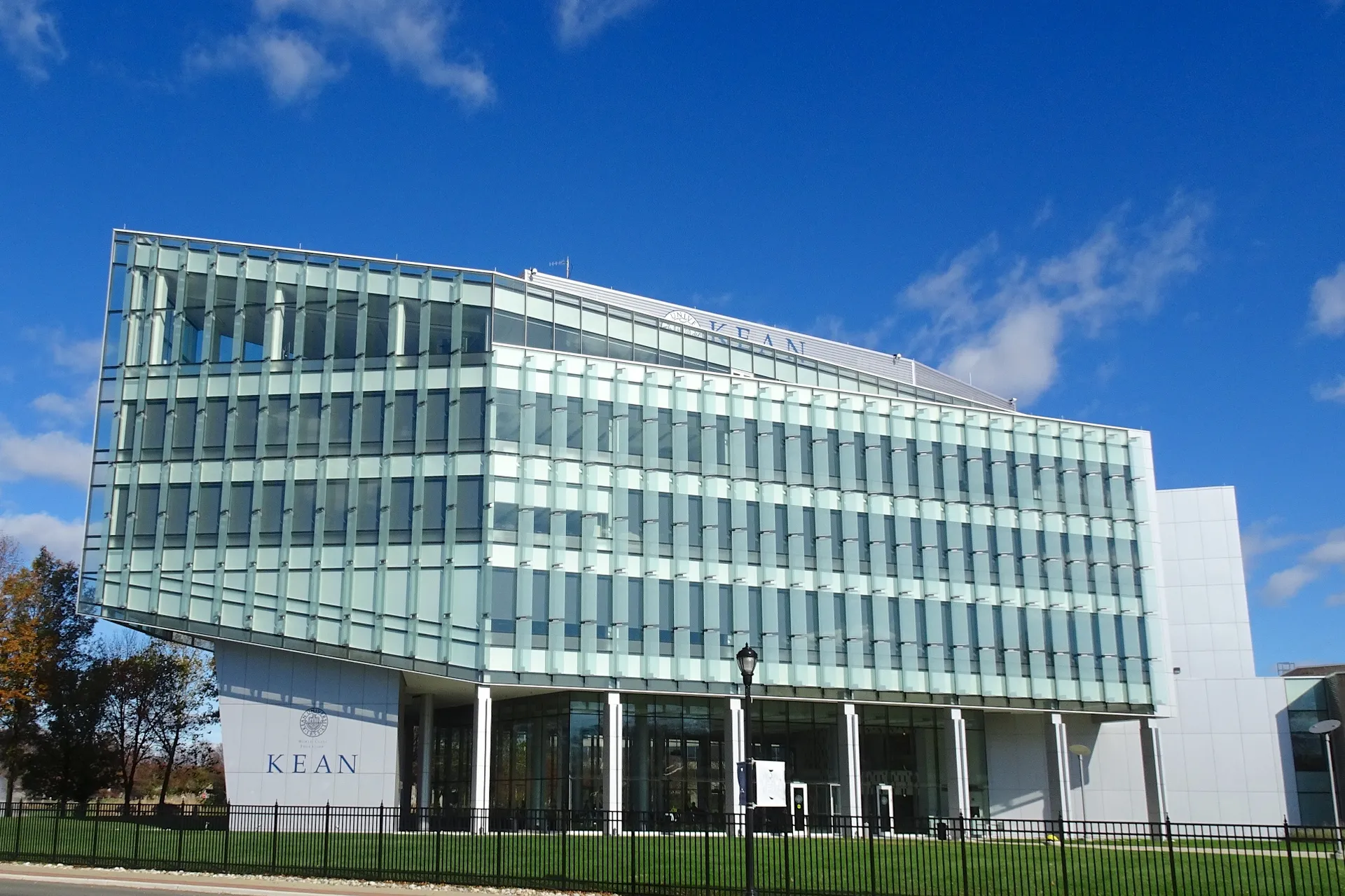 The STEM Building at Kean University is a modern multistory structure wrapped in glass and white horizontal bands.