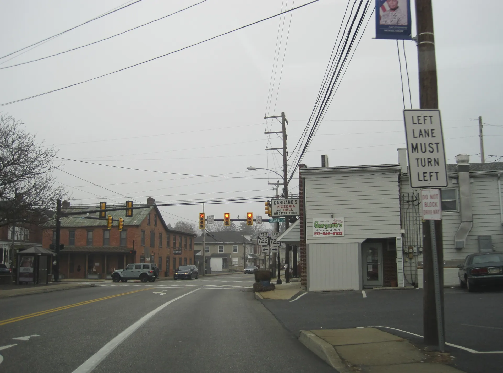 Main Street (Route 72) in East Petersburg crosses State Street beneath traffic signals, flanked by brick buildings and shops.