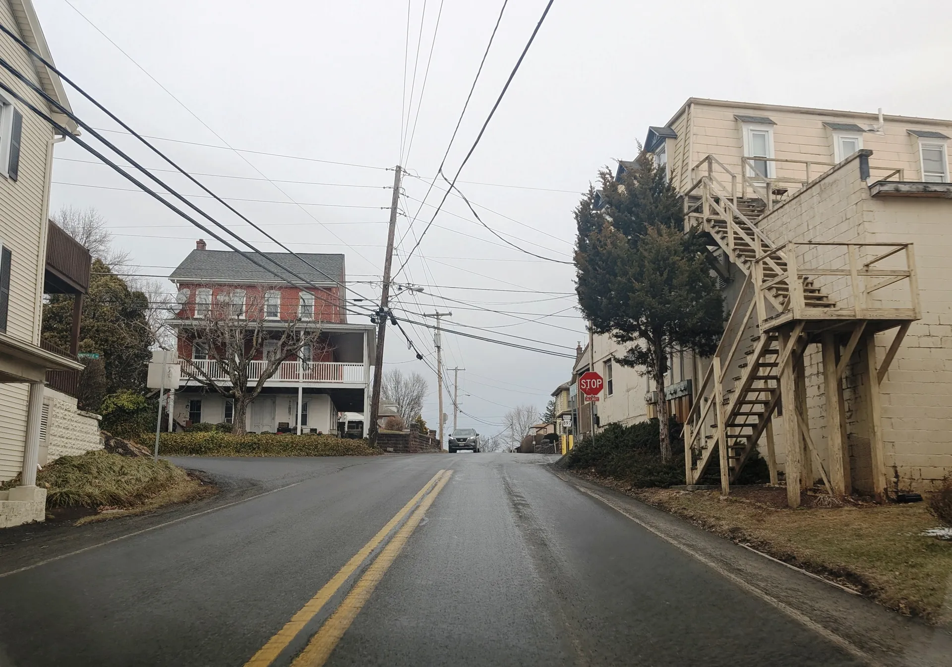 Dry Tavern Road (Route 897) runs through Fivepointville past brick houses and a tall frame building on a cloudy winter day.
