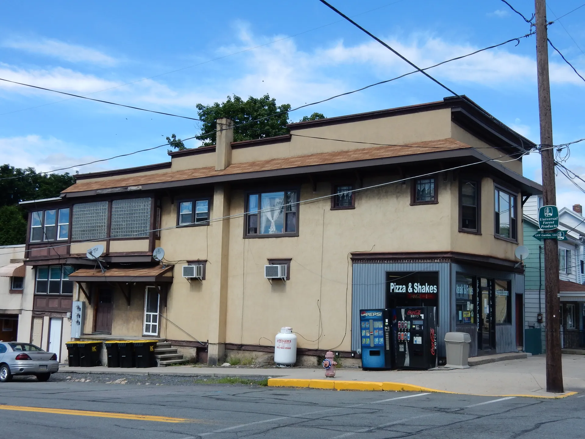 A café occupies a tan corner building with storefront windows on Biddle Street in Gordon.