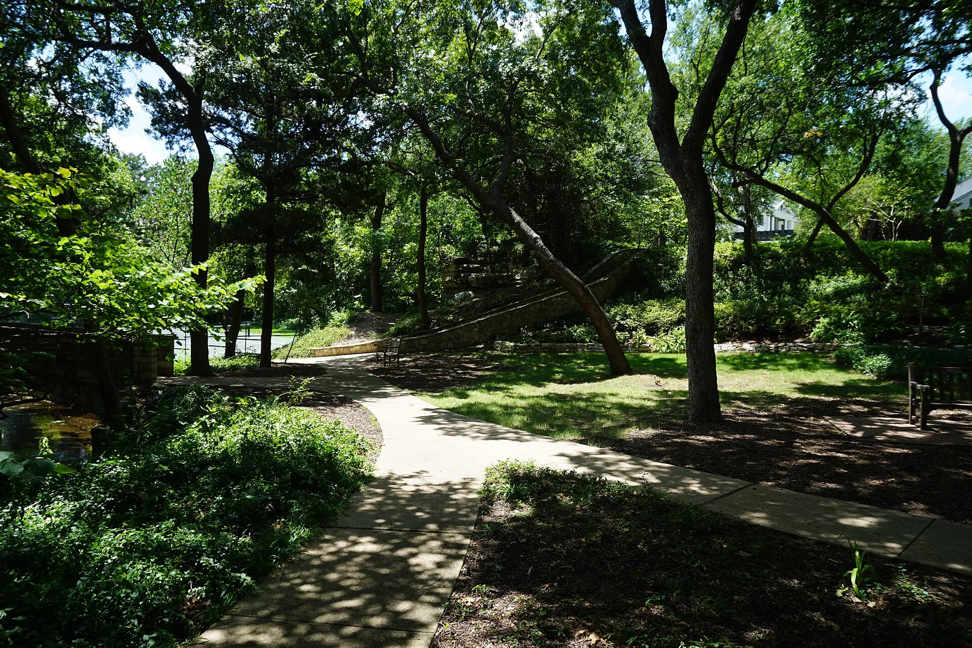 Shaded walking path under tall trees in Prather Park, Highland Park, Texas.