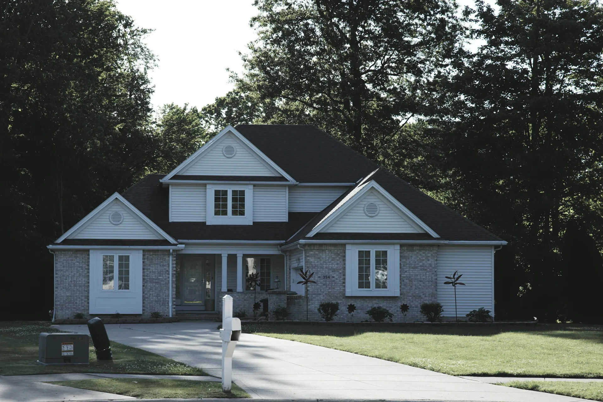 A residential house with a green lawn and trees.