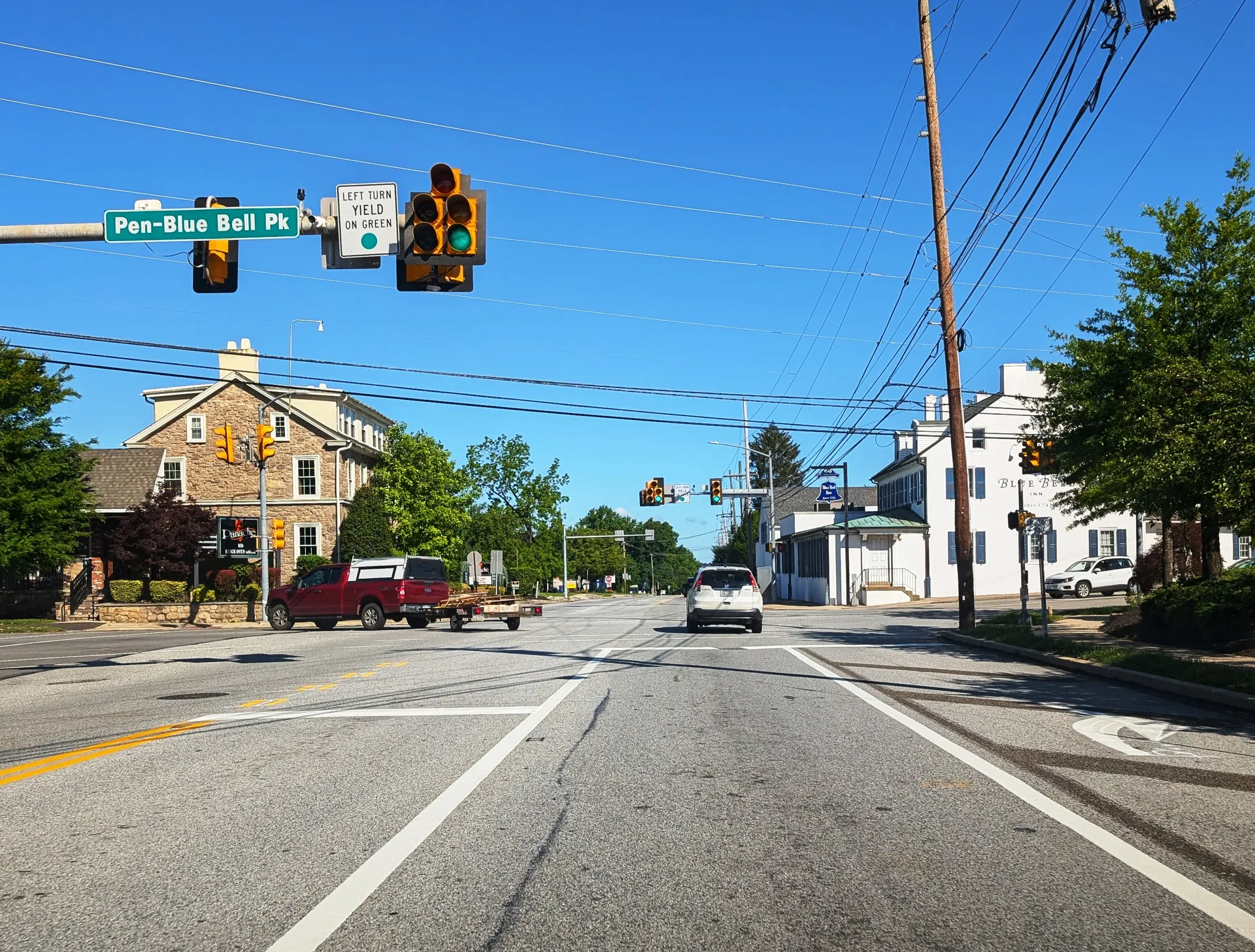 Skippack Pike (Route 73) crosses Penllyn-Blue Bell Pike in Blue Bell, where traffic signals hang over older stone and frame buildings.