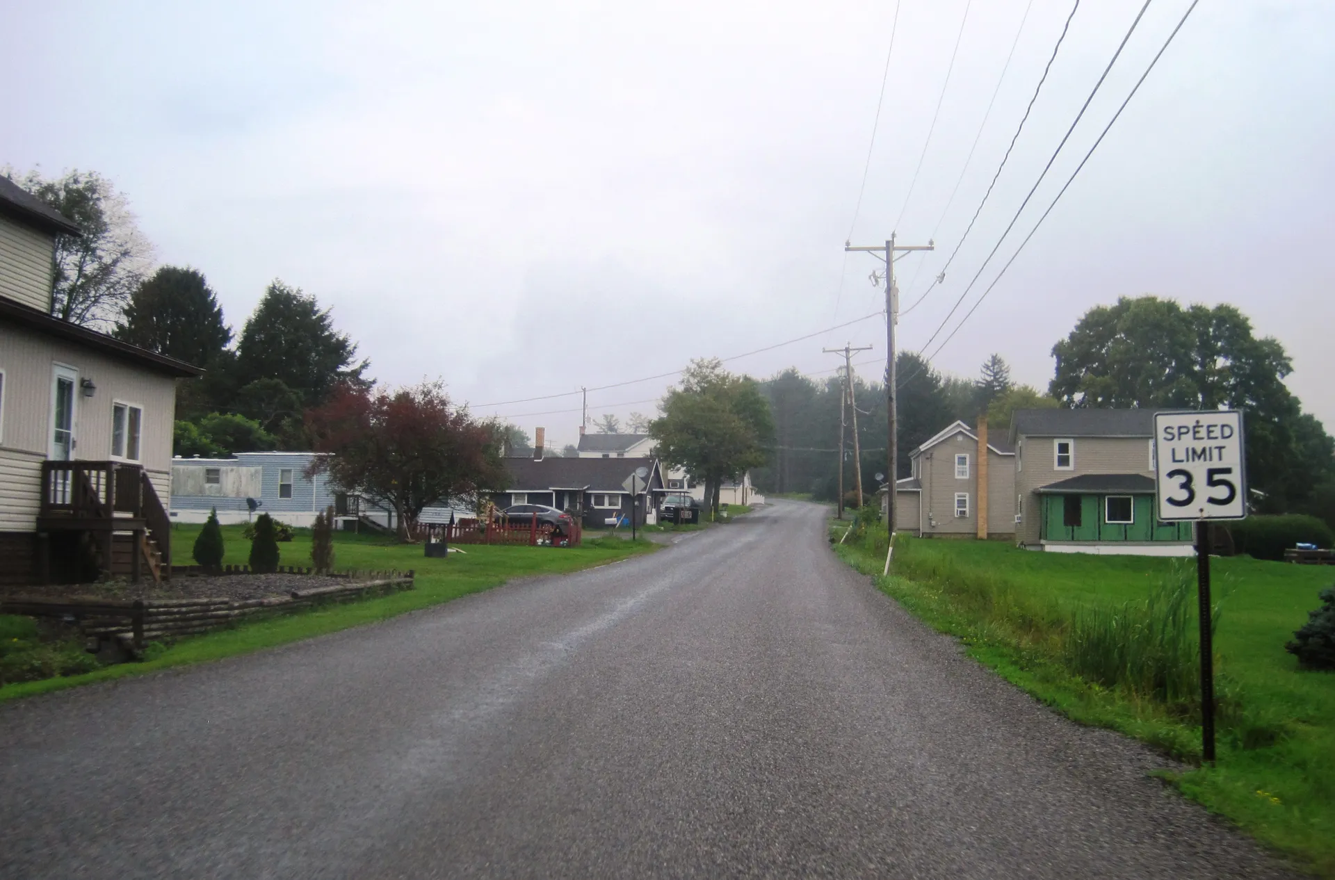 Powell Street leads east through the small village of Hawk Run in Morris Township, past houses and a roadside fence.