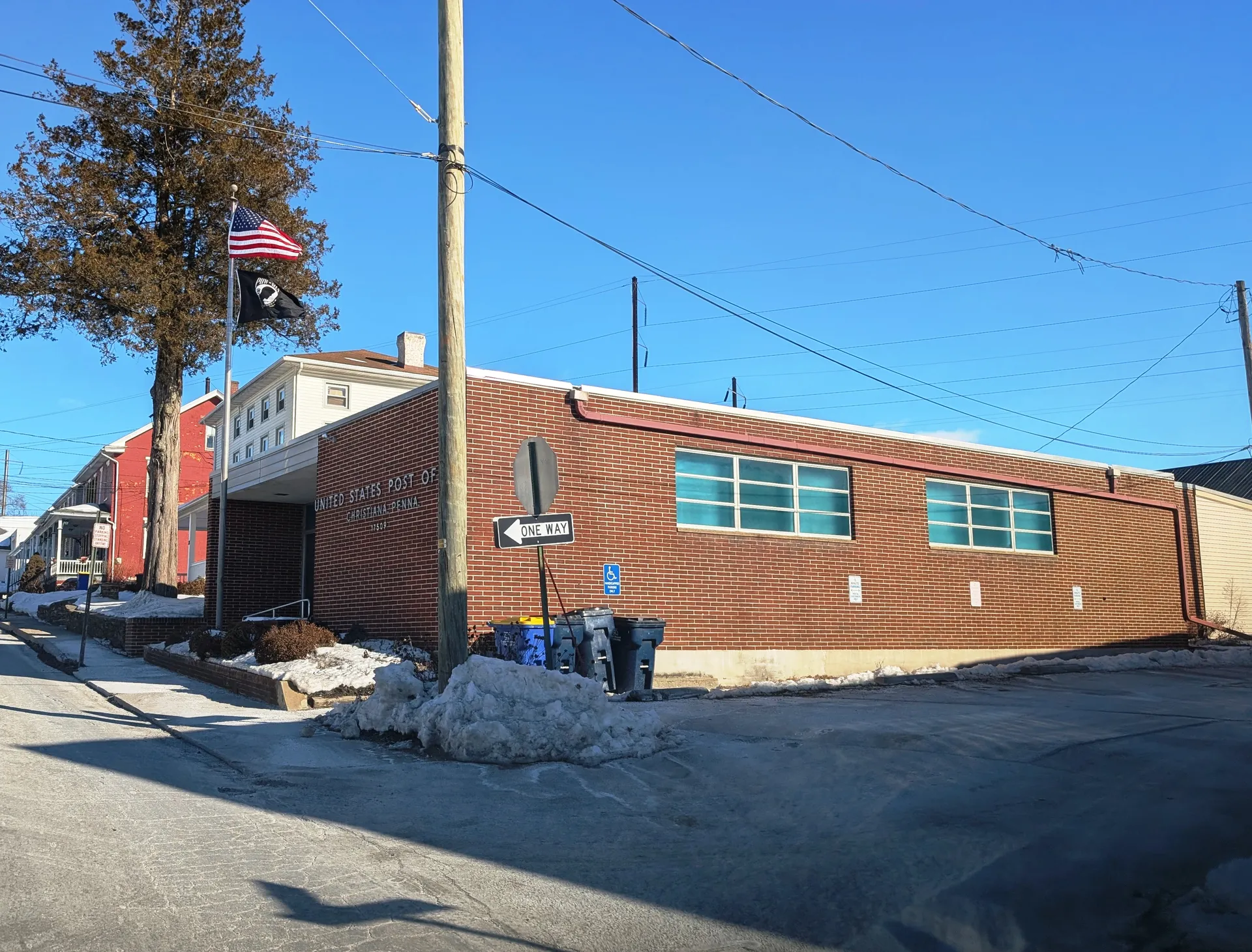 Christiana's post office is a brick building with large glass-block windows, with snow piled along the street in front.