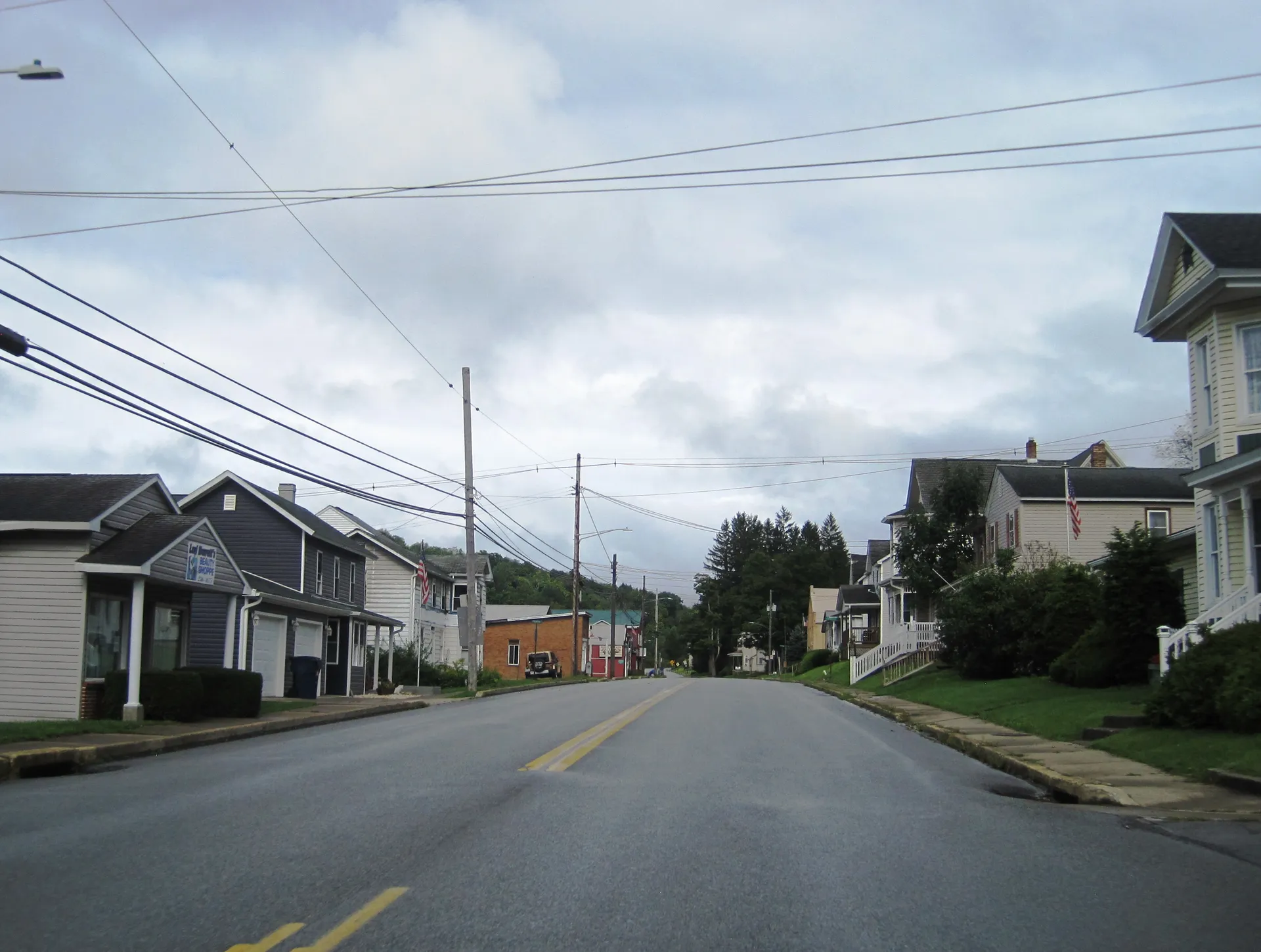 Main Street (U.S. Route 219) in Grampian heads west-northwest at 3rd Street past frame houses and utility lines.