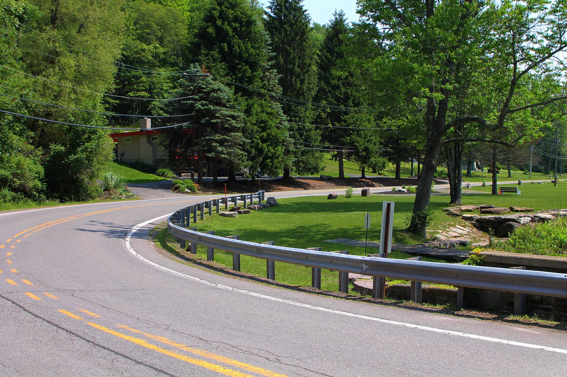 Route 415 bends past wooded slopes and a guardrail in the southwestern part of Harveys Lake borough.