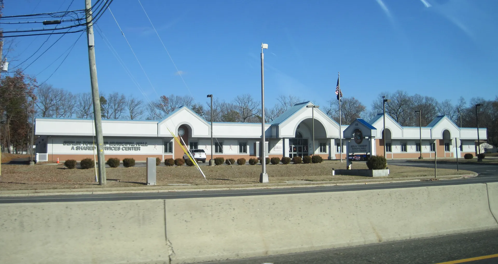 Berlin Township's municipal hall is a long white building with twin arched gables, flags flying out front along the roadside.