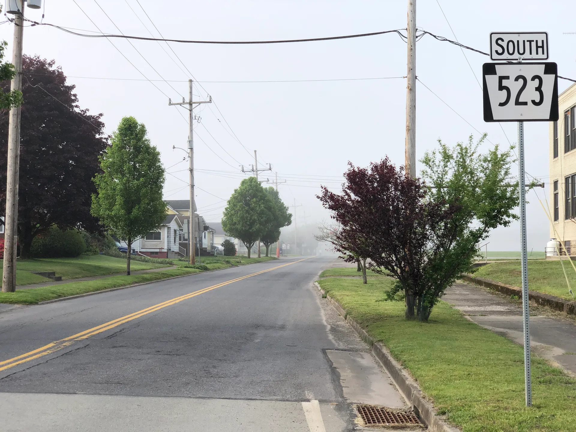 Oden Street (Route 523) in Confluence heads south from Robert Brown Road past houses, lawns and a flowering tree.