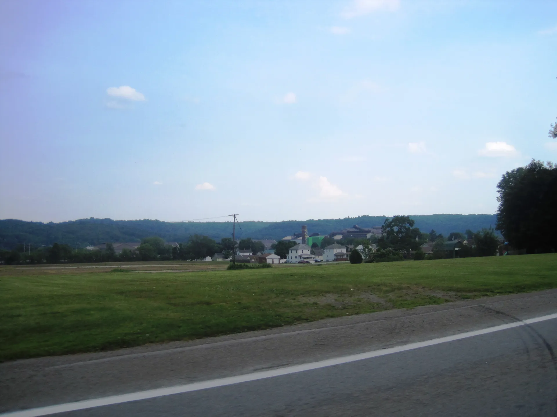 Seen from Route 18, the borough of Koppel spreads across a hillside beyond a broad green field.