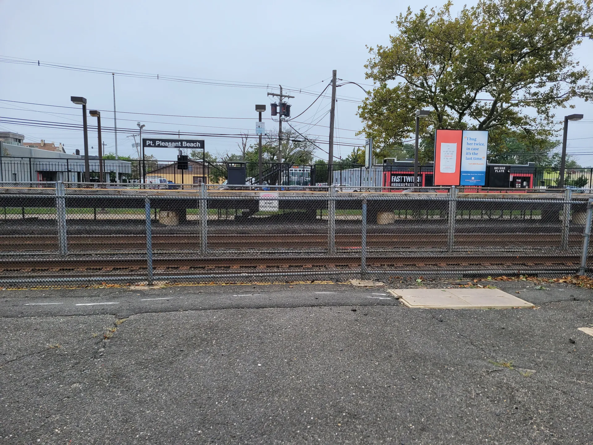The Point Pleasant Beach train station sits beside the tracks with its platform and crossing signals.