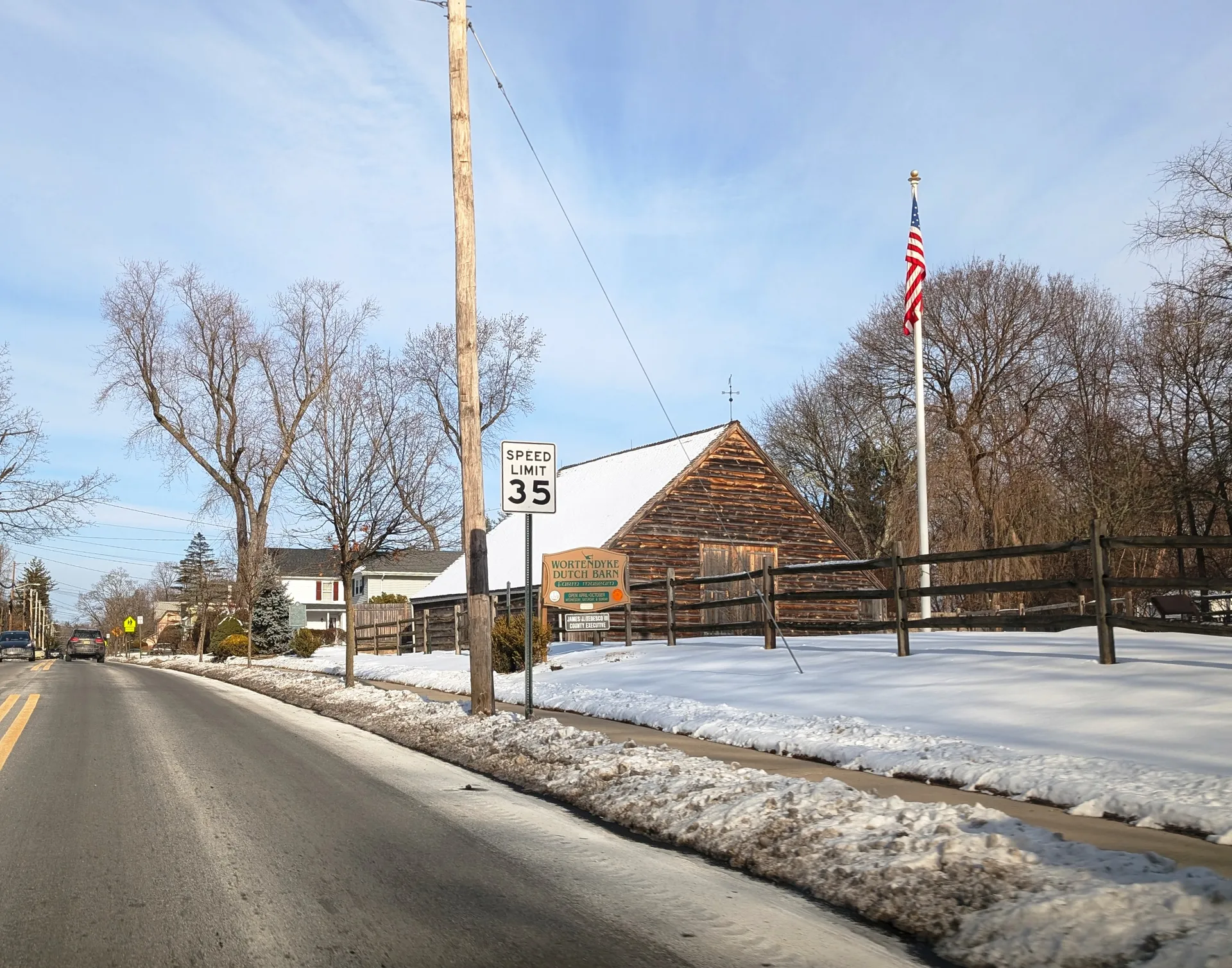 The Wortendyke Dutch Barn in Park Ridge is a broad red-brown barn with a steep gable beside a snowy roadside.