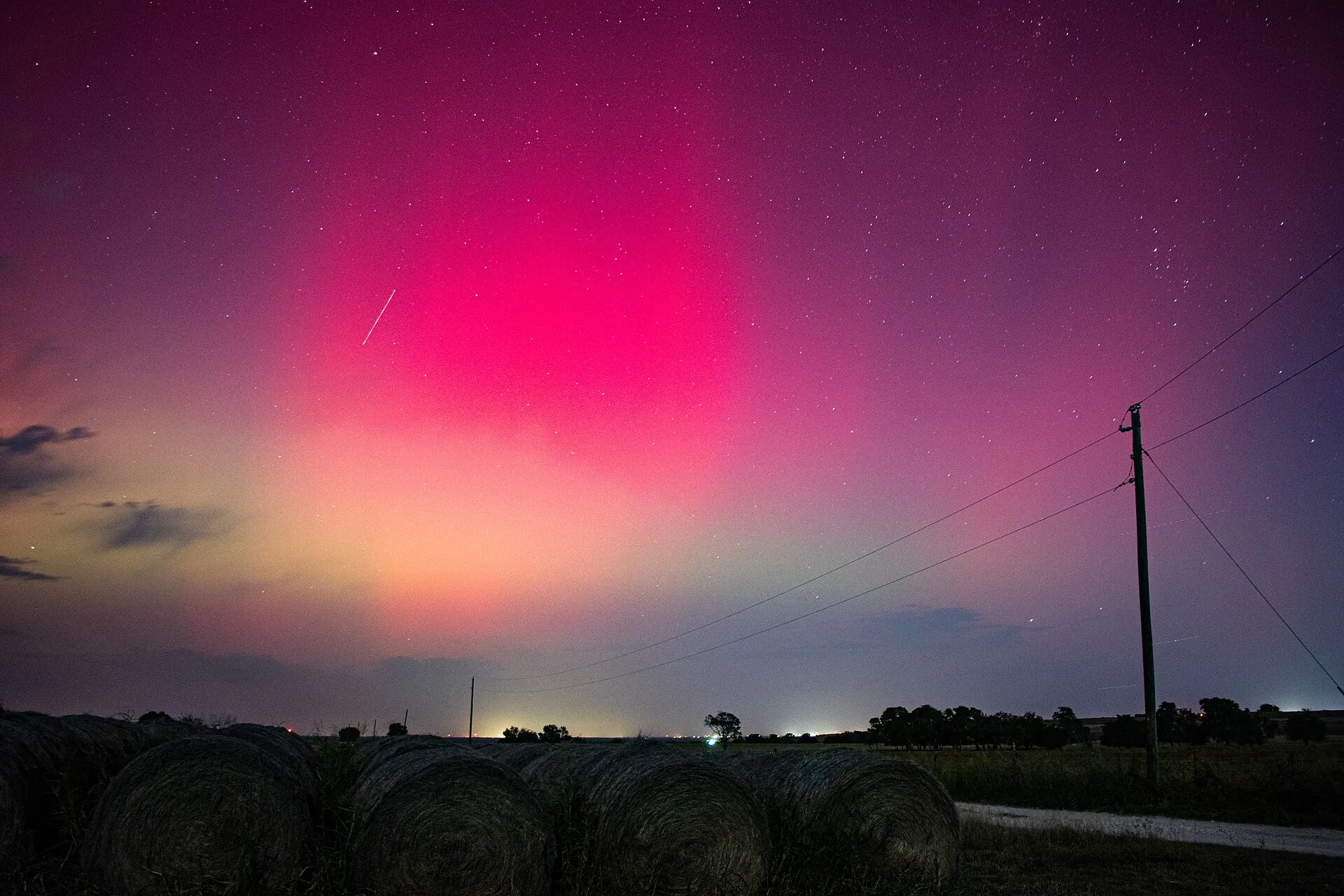 Northern lights glowing pink and green over the horizon near Aurora, Texas.