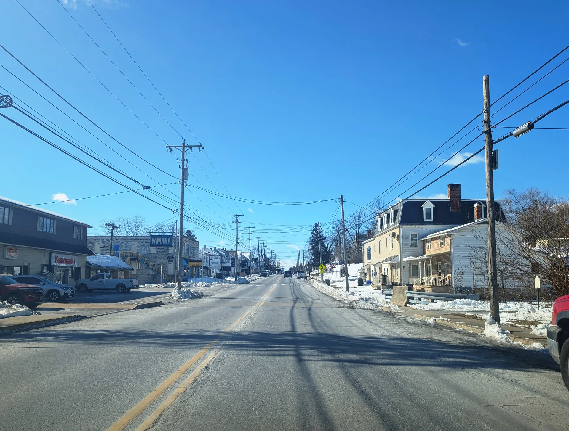 In Hallam, East Market Street carries the Lincoln Highway westward past shops, snowbanks and a row of homes near Prospect Street.