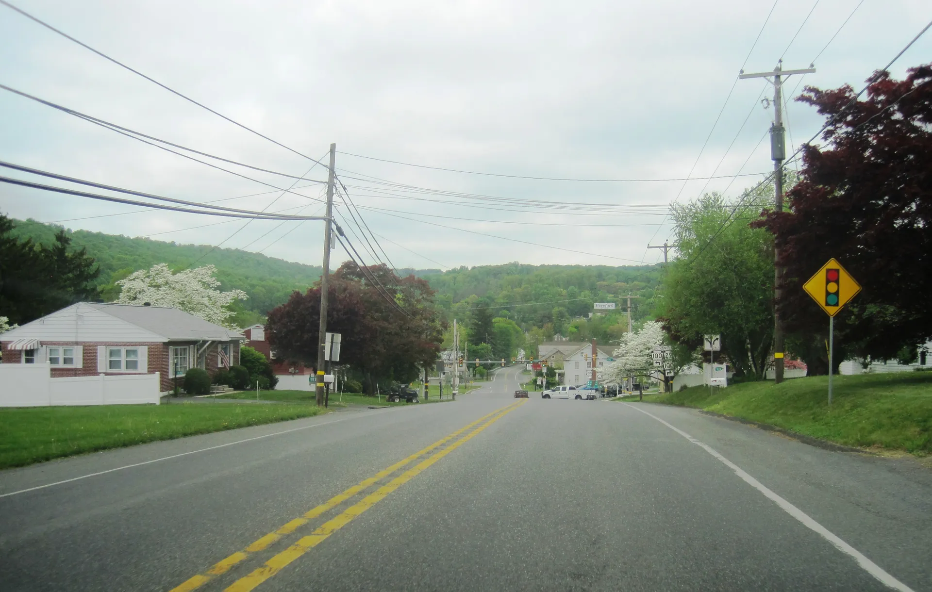 Gravel Pike (Route 29) descends into the village of Hereford, where houses cluster along the road below a wooded ridge.